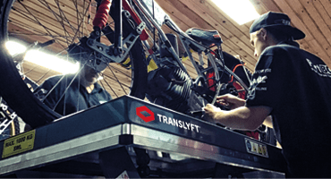 personas limpiando una moto de speedway en una mesa elevadora translyft